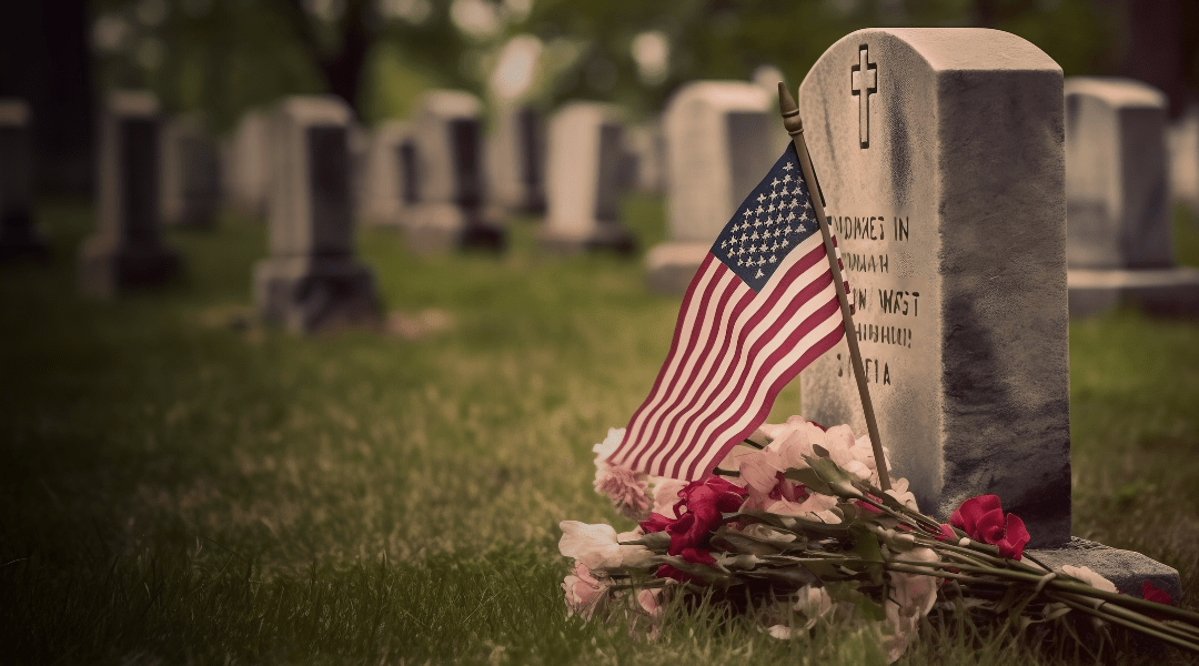 American flag and flowers placed at a soldier's grave, symbolizing Memorial Day remembrance.