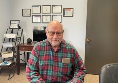 An older gentleman over 65 smiling in Mark Duprè's office after securing the best Medicare plan tailored to his needs with MLD.