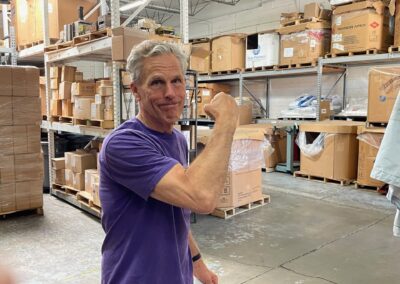 An older businessman flexing his bicep in his warehouse, feeling strong and protected by MLD's group business insurance solutions in Illinois.